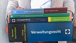 Eine Person trägt mehrere Bücher zum Thema Verwaltung