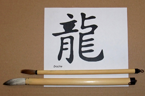 Zwei Kalligrafiepinsel liegen auf einem weißen Papier mit chinesischen Schriftzeichen