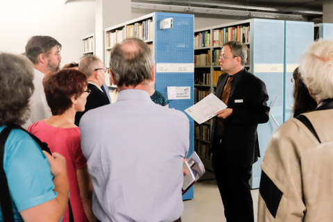 Besuchergruppe mit Bücherregalen im Hintergrund, ein Gästeführer erläutert das Magazin der Deutschen Nationalbibliothek in Frankfurt am Main