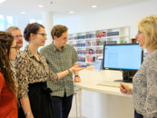 Eine Gruppe Benutzer*innen steht bei einer Benutzungseinführung im Lesesaal um einen Katalogbildschirm herum