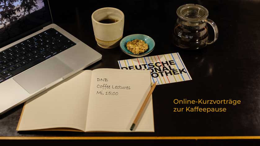 Tisch mit einem aufgeklappten Laptop, einem Kaffee und einemn Notizbuch, darauf steht „ DNB, Coffee Lectures, Mi, 15 Uhr“. 