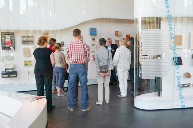 Gästegruppe vor Vitrinen der Ausstellung "Zeichen - Bücher Netze" des Deutschen Buch und Schriftmuseums in Leipzig