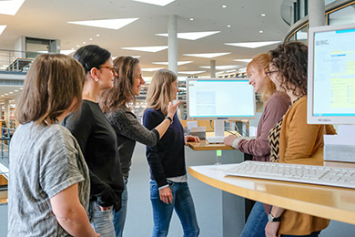A group of users stand around a catalogue screen in the reading room