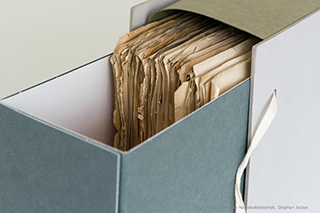An open archival box with papers