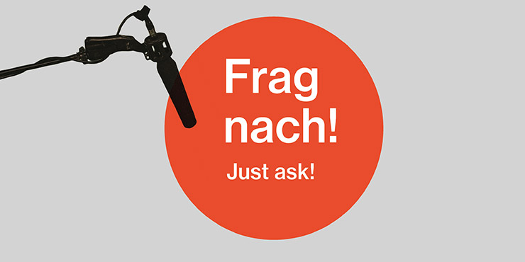 Graphic, red circle with the lettering "Frag nach, Just ask!", background grey